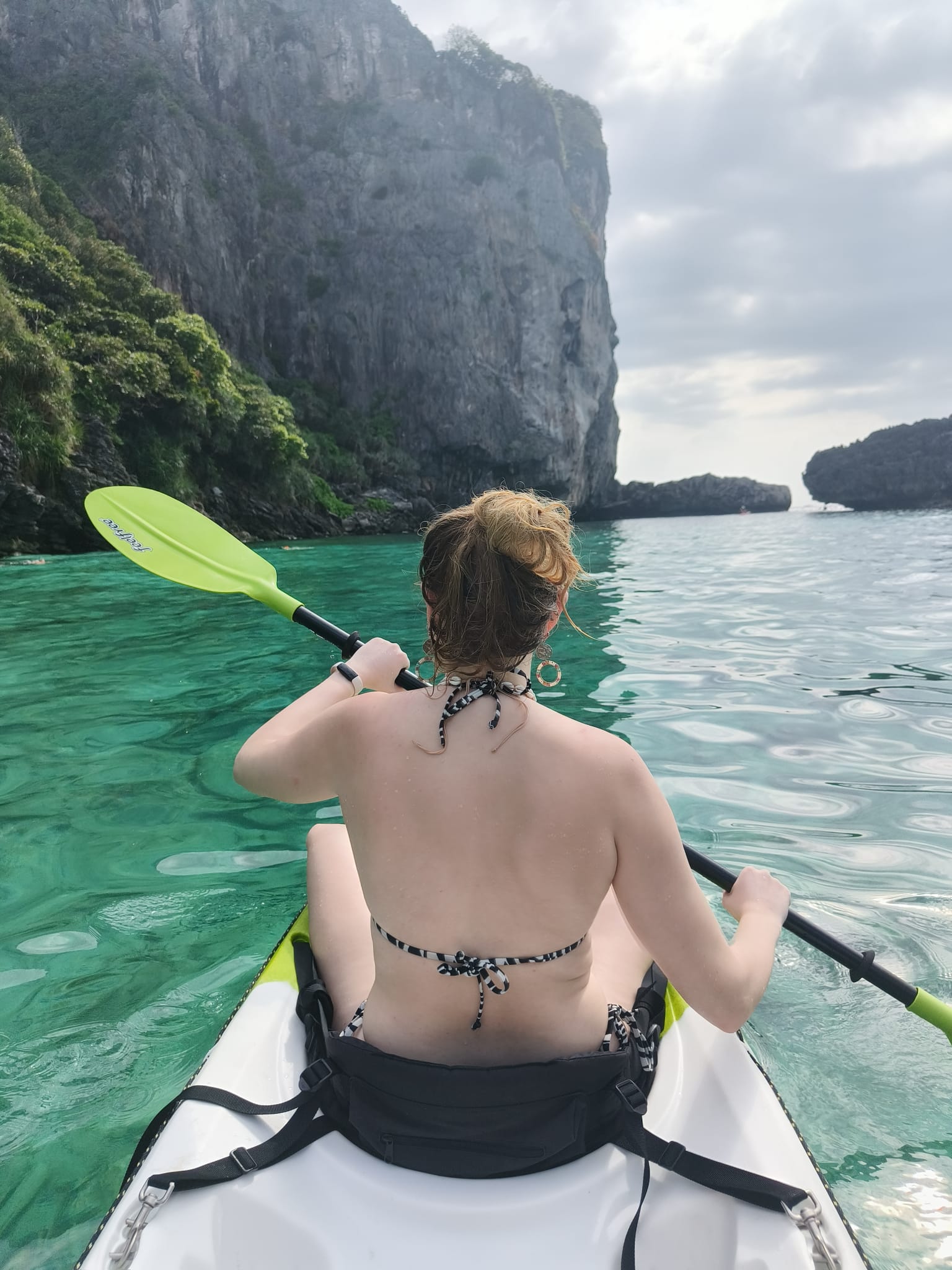 Peddelen in een kajak over het heldere groene water langs de rotswanden van Koh Phi Phi