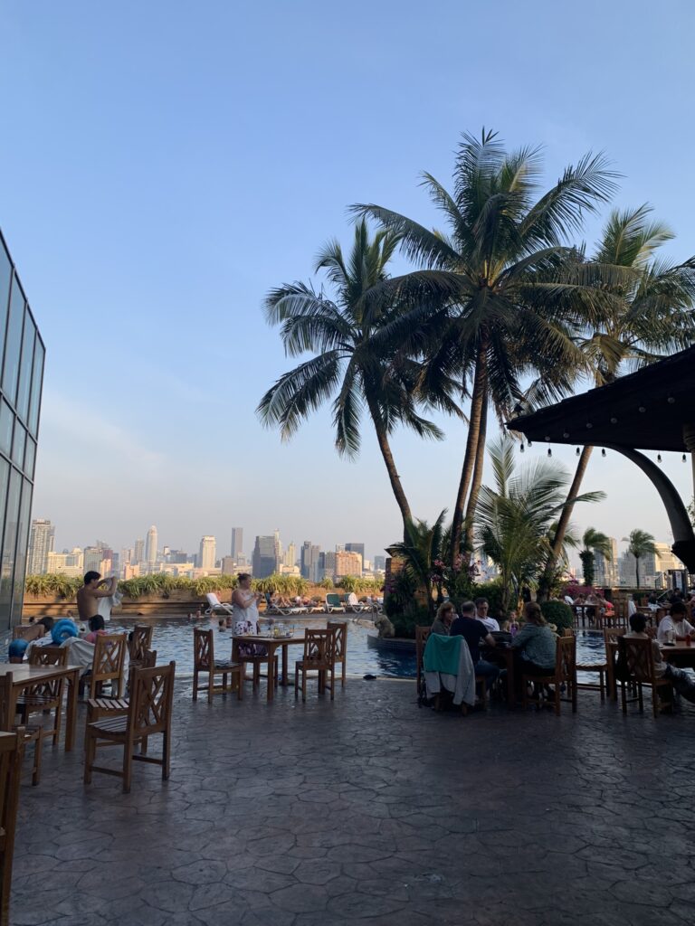 Uitzicht vanaf een sfeervol dakterras met palmbomen over de skyline van Bangkok