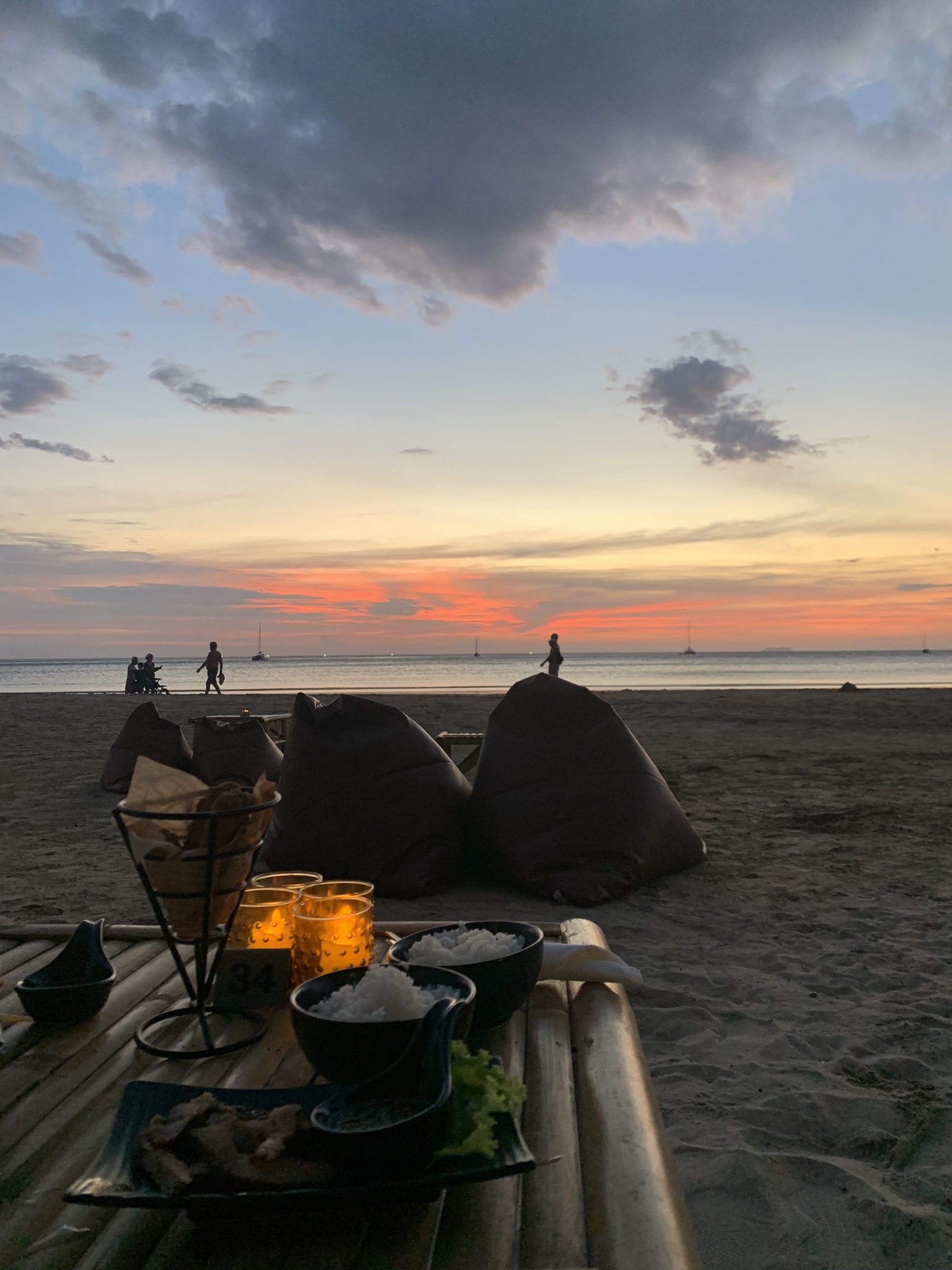 Genieten van cocktails en Thais eten op het strand tijdens een kleurrijke zonsondergang op Koh Lanta