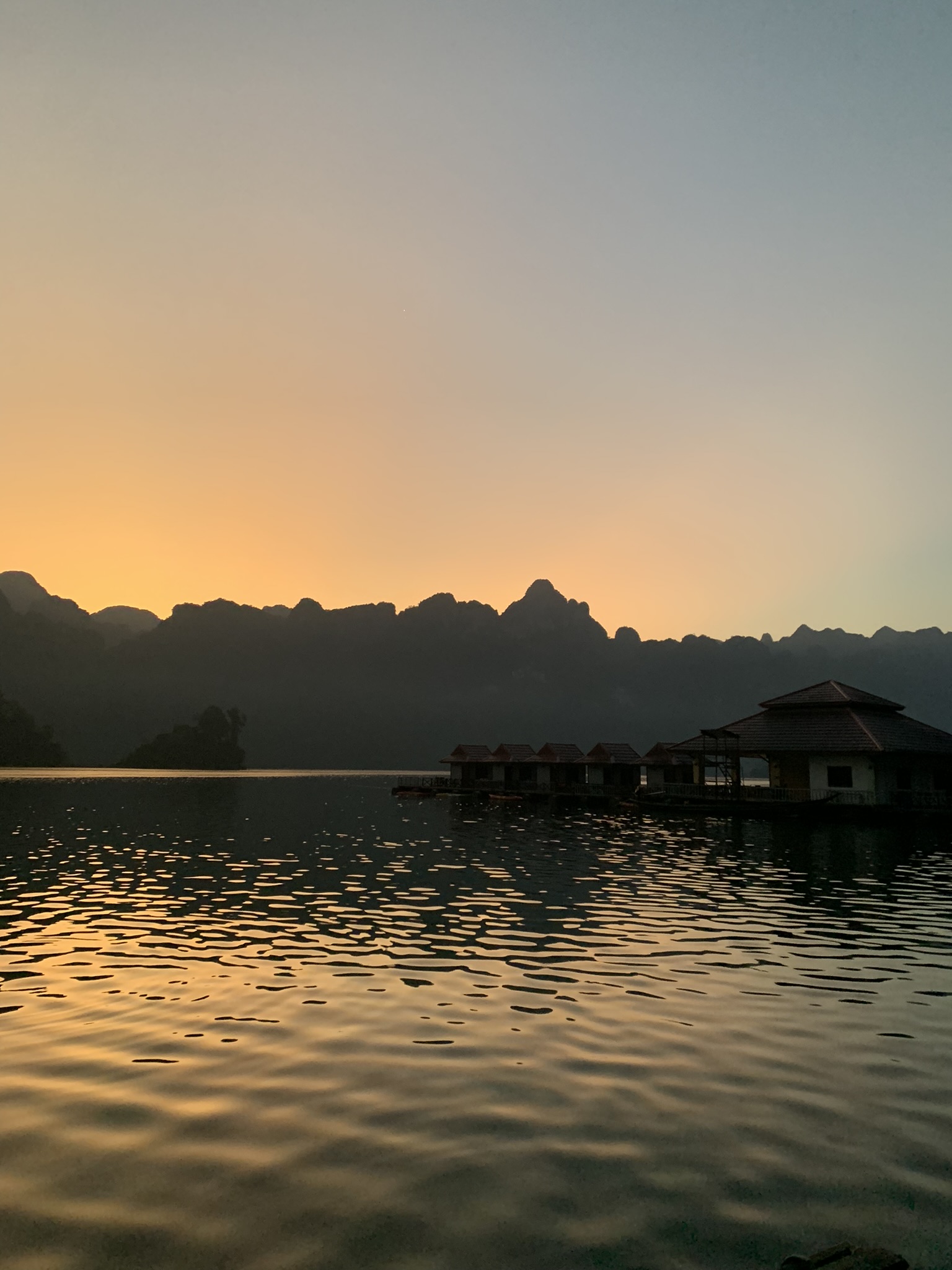 Sfeervolle zonsondergang boven de bergen en drijvende huisjes van Khao Sok National Park