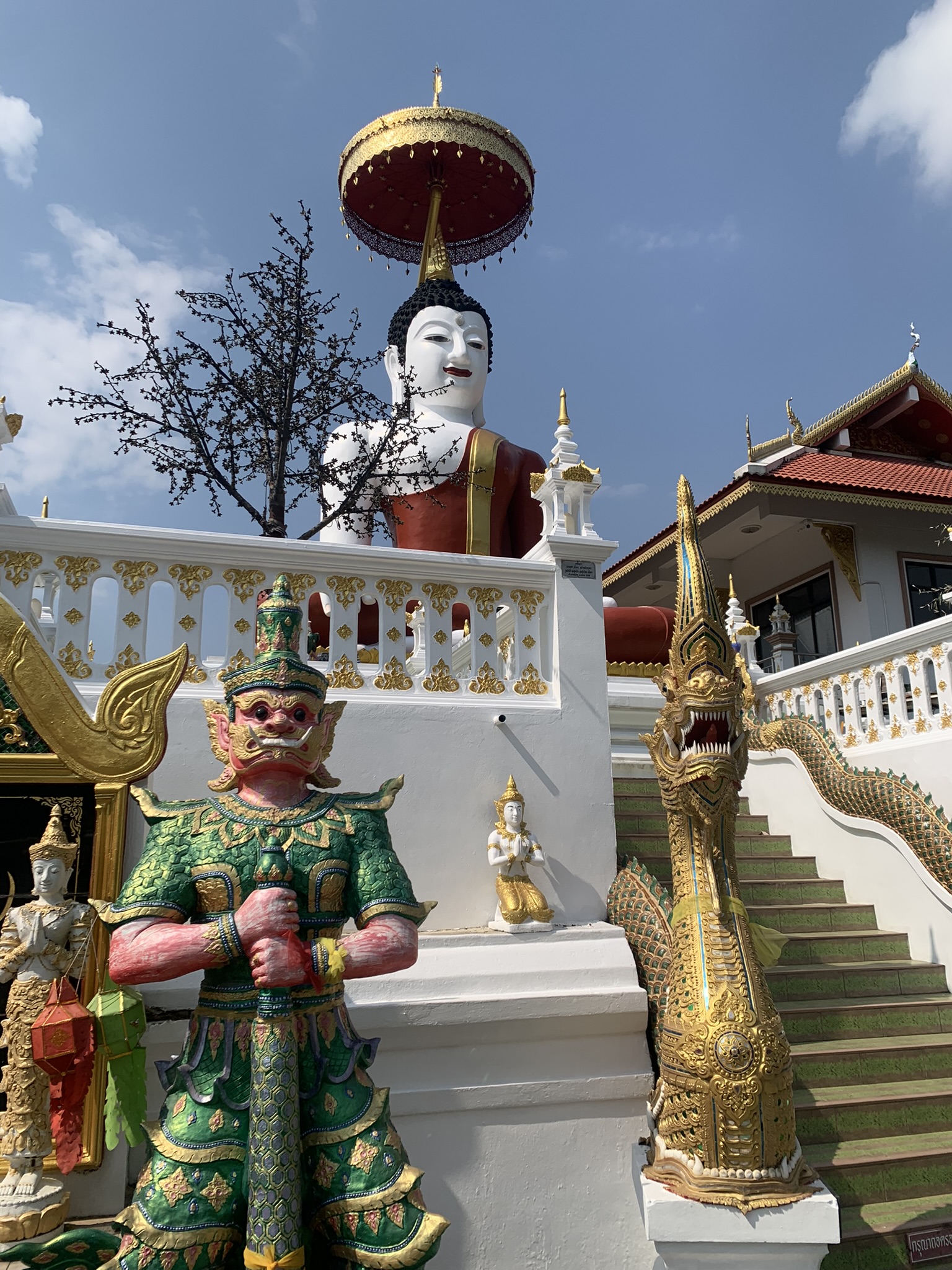Indrukwekkende witte tempel met kleurrijke standbeelden en gouden details in Thailand