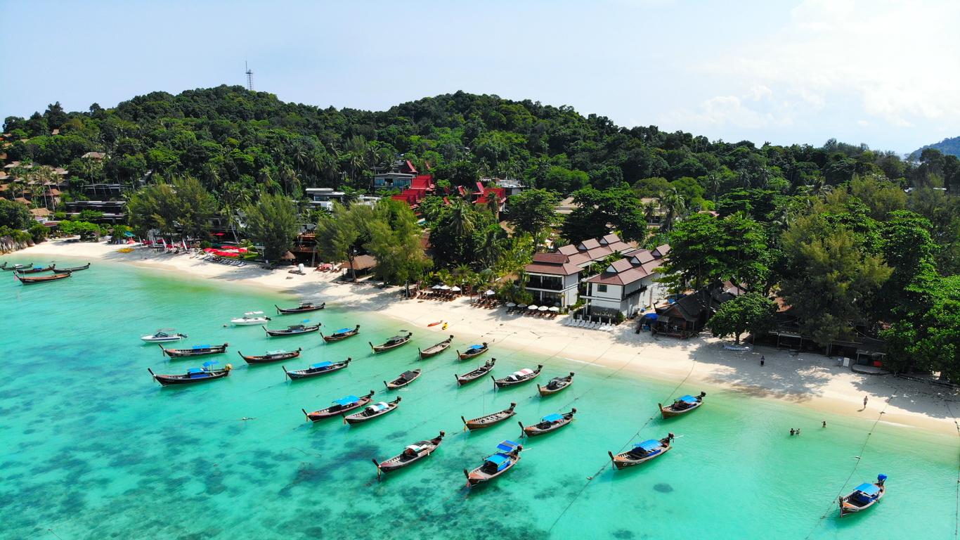 Luchtfoto van een hagelwit zandstrand op Koh Lipe met talloze houten longtailboten in het helderblauwe water