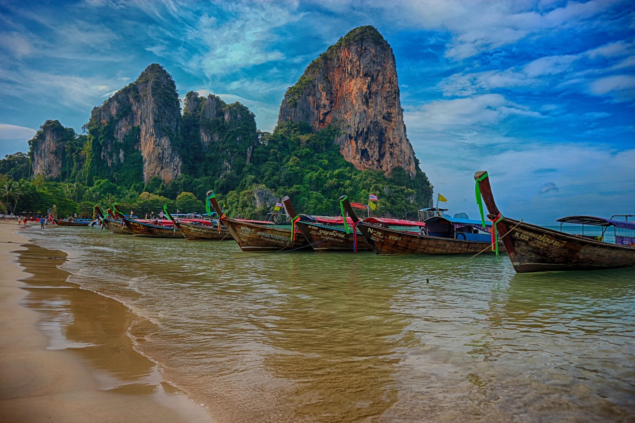 Een rij kleurrijke Thaise longtailboten klaar voor vertrek vanaf het strand van Railay Beach in Krabi