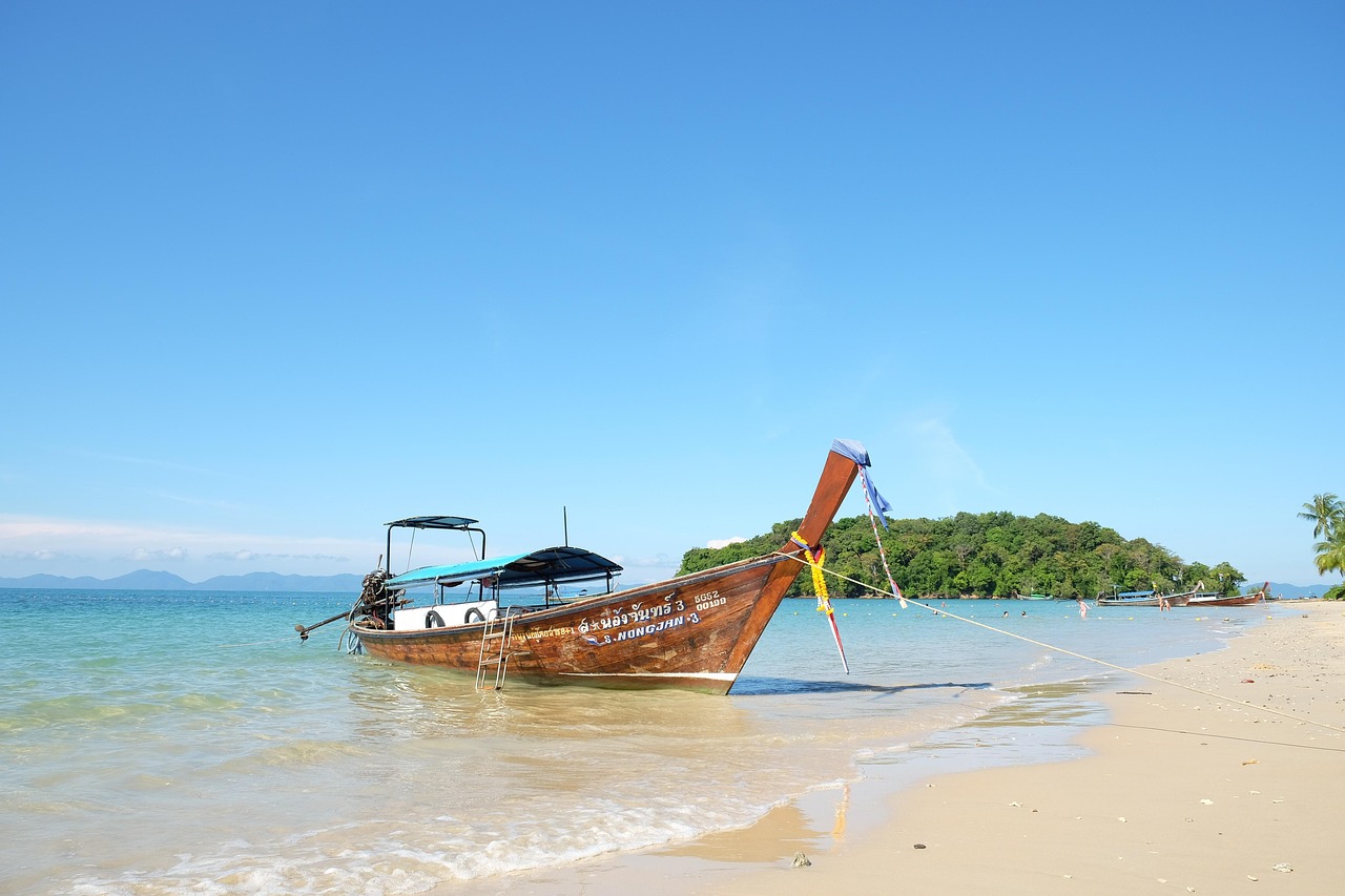 Een eenzame houten boot drijvend op het kristalheldere turquoise water van een tropisch eiland bij Krabi