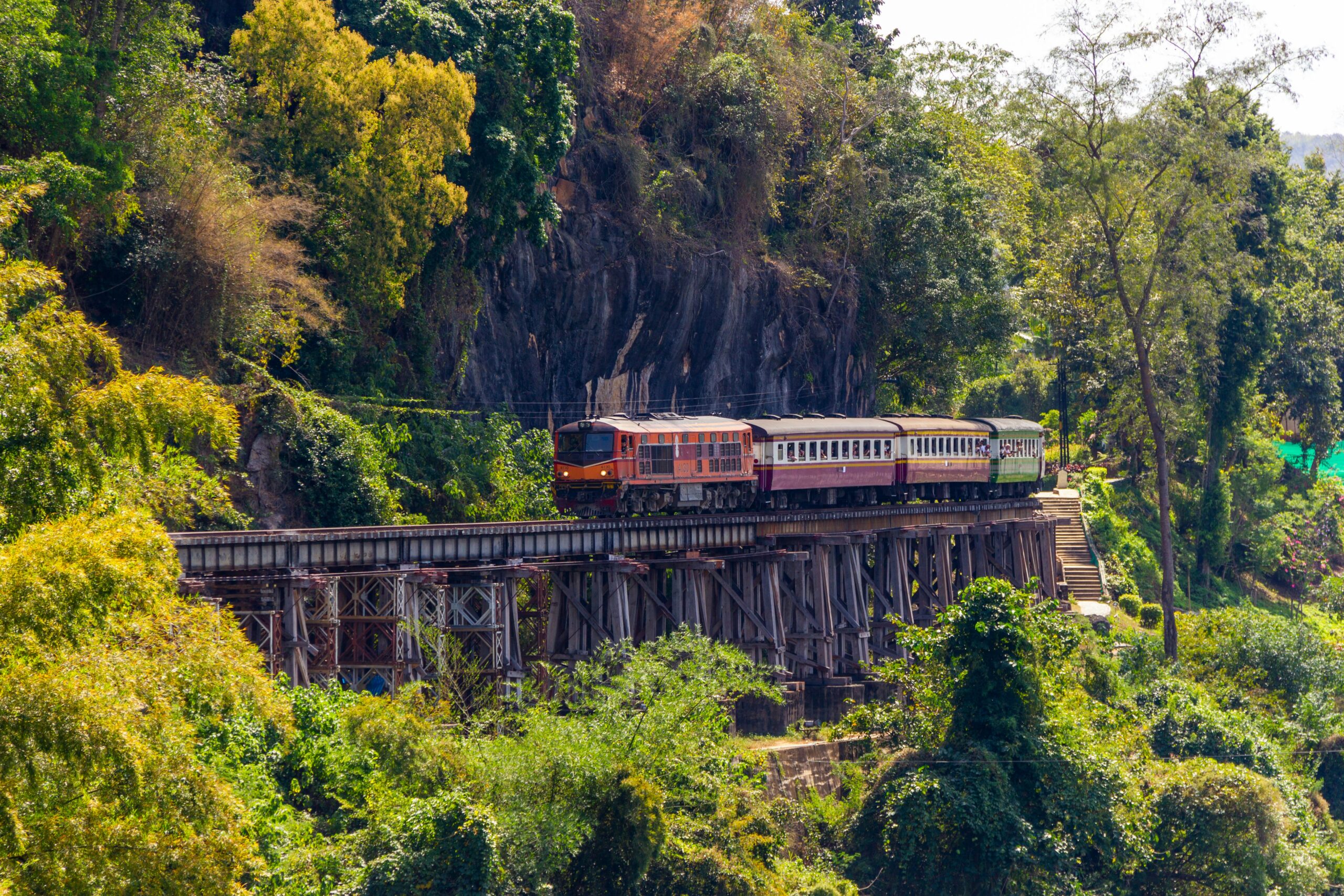 De beruchte Death Railway trein die over het houten viaduct langs de rivier bij Kanchanaburi rijdt