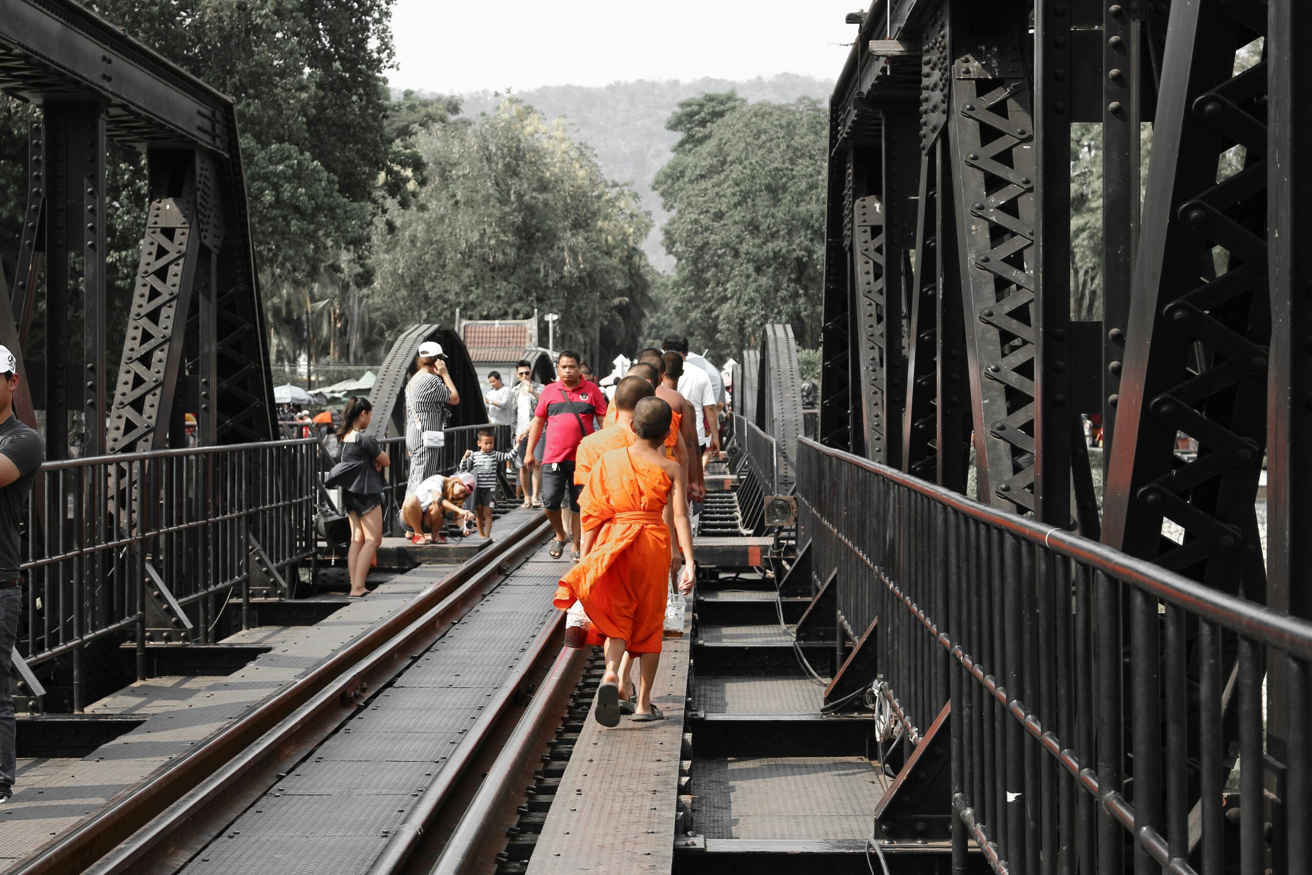 Bezoekers en een monnik wandelen over de beroemde Bridge over the River Kwai in Kanchanaburi
