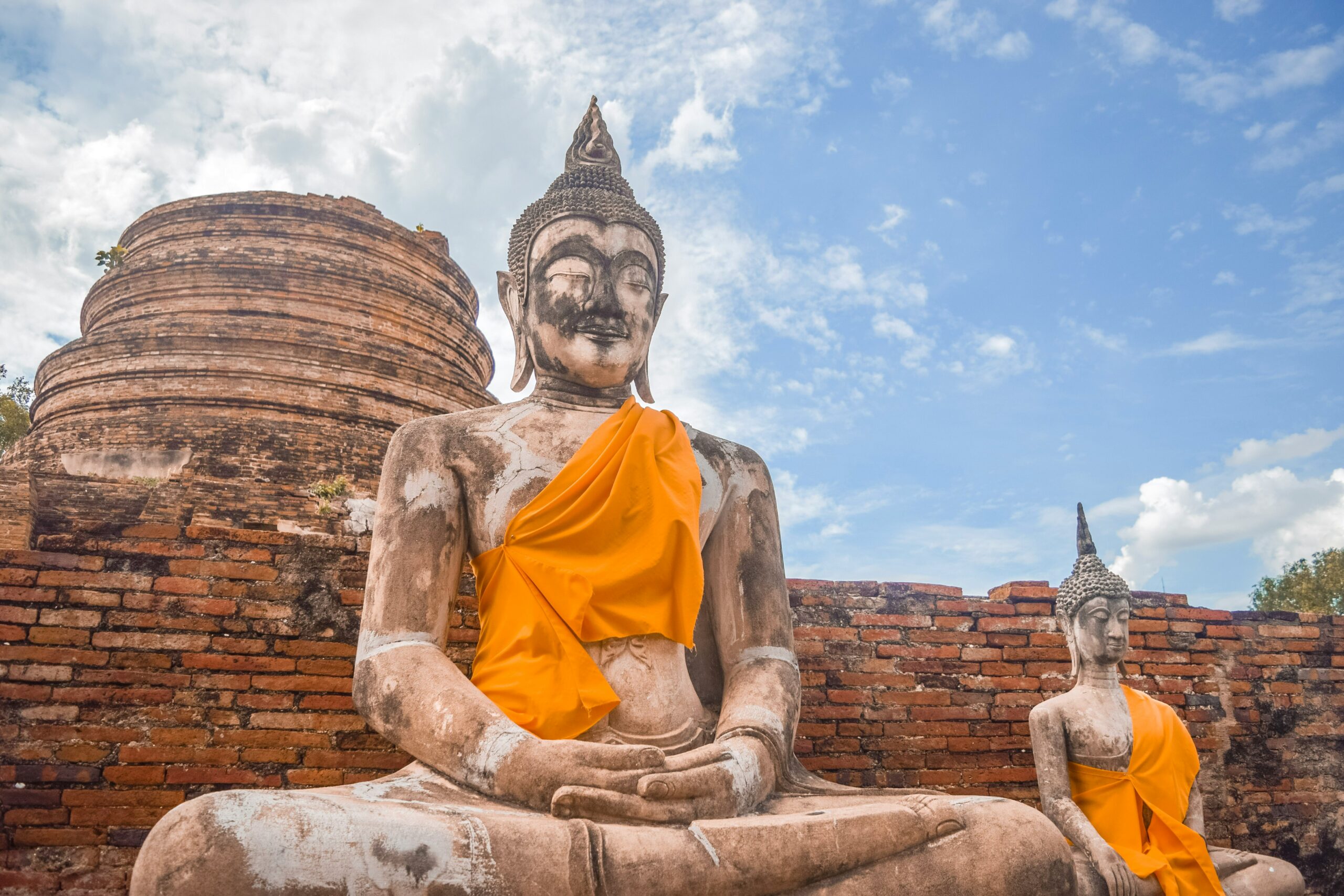 Een groot zittend Boeddhabeeld met een oranje gewaad bij de historische Wat Yai Chai Mongkhon tempel in Ayutthaya