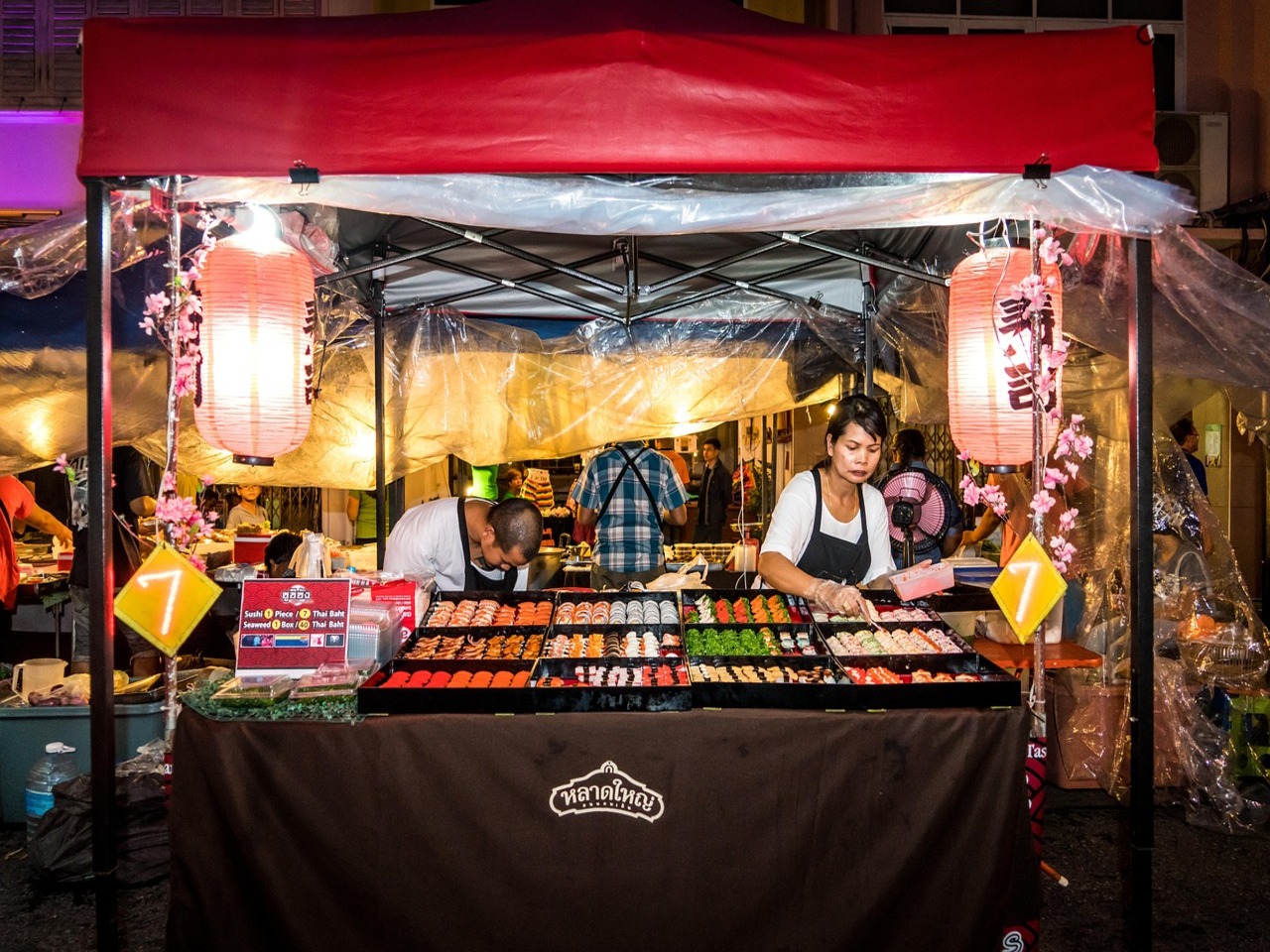Lokale verkoper bij een gezellige streetfood kraam op de avondmarkt van Phuket