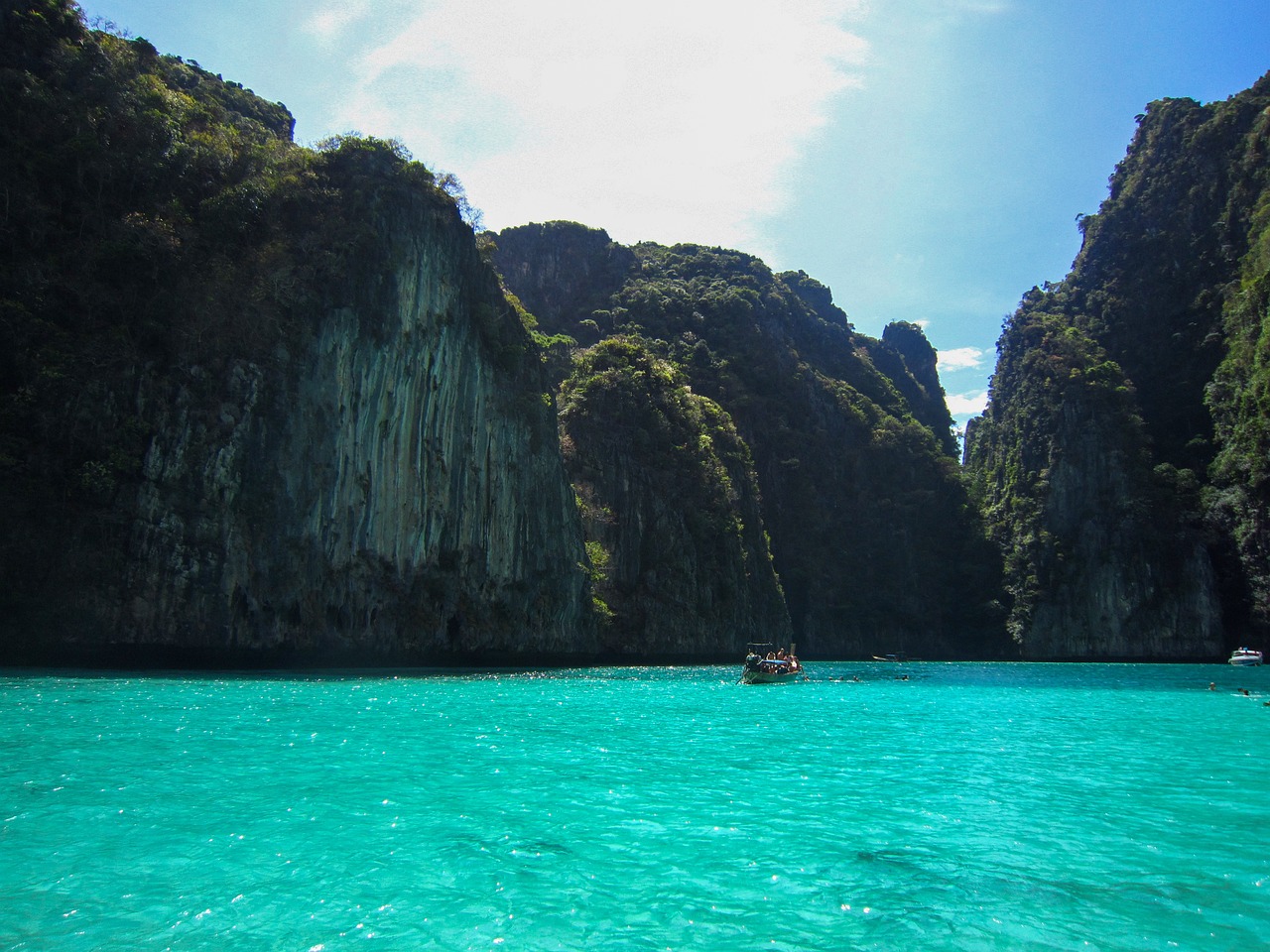 Kristalhelder turquoise water van een baai omringd door steile groene rotsen bij Phuket